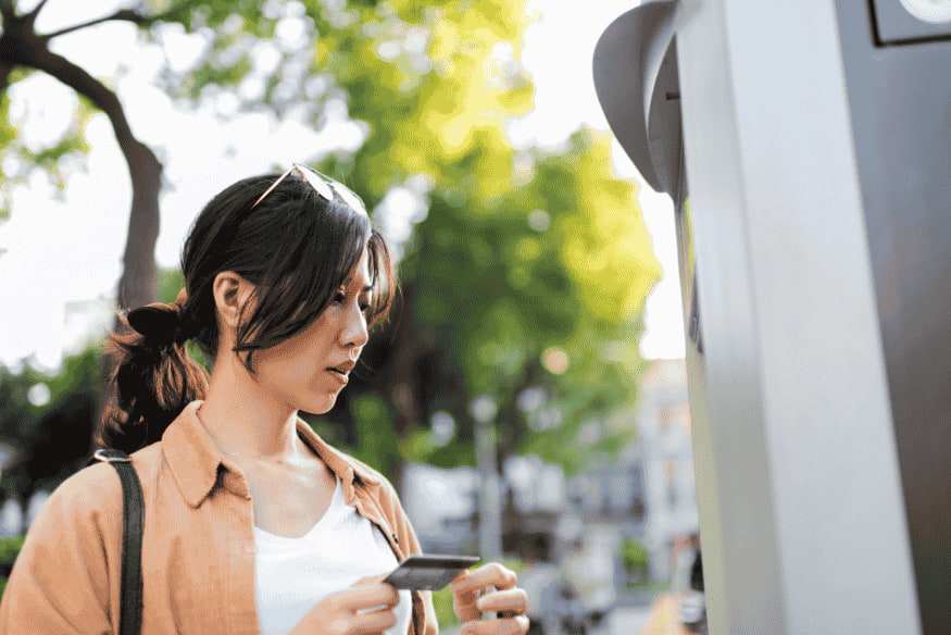 Mulher utilizando cartão de crédito em caixa eletrônico como símbolo de inclusão financeira para quem tem score baixo