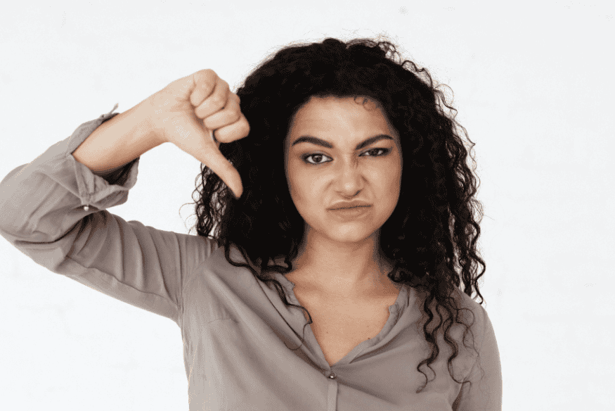 Mulher mostrando desaprovação ao avaliar as desvantagens do cashback em cartões de crédito