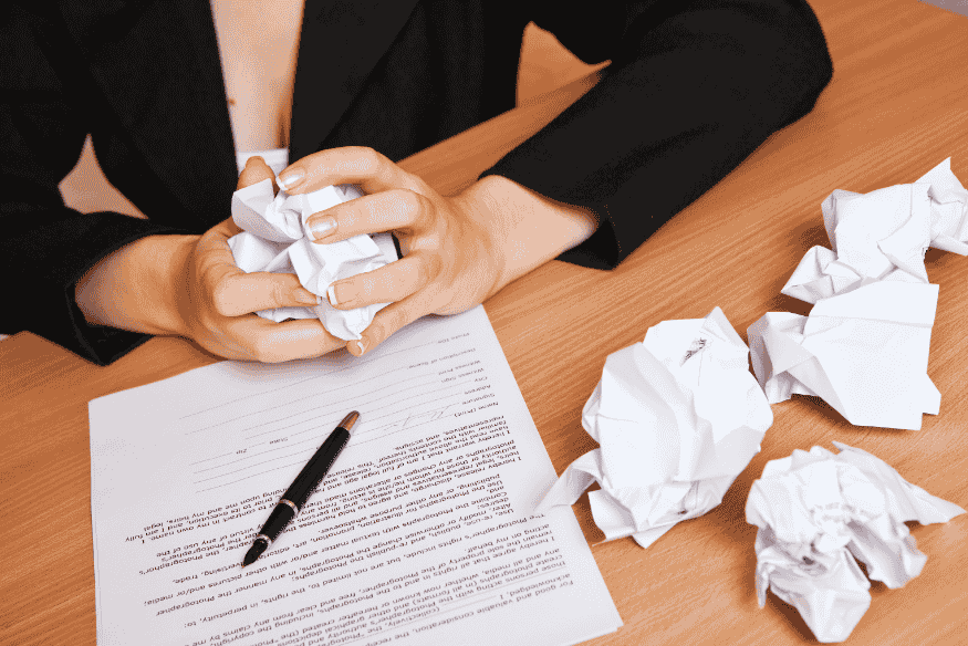 Pessoa amassando papéis de cobrança indevida sobre a mesa, representando frustração e a busca por soluções legais para proteger seus direitos financeiros.