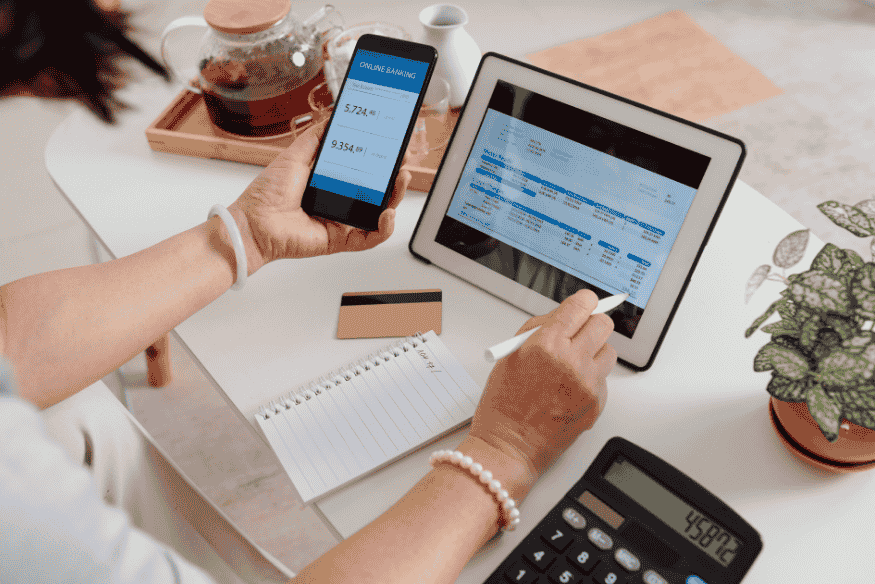 Pessoa consultando saldo bancário e histórico financeiro em dispositivos móveis e tablet, com foco na gestão de contas.