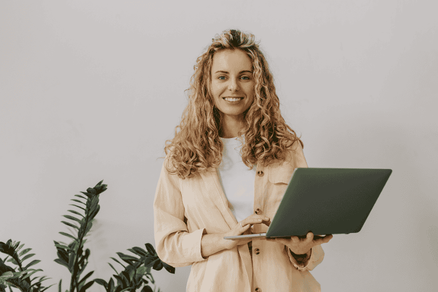 Mulher sorridente segurando um notebook, representando a importância de atualizar dados cadastrais para reconstruir o crédito com segurança após limpar o nome.
