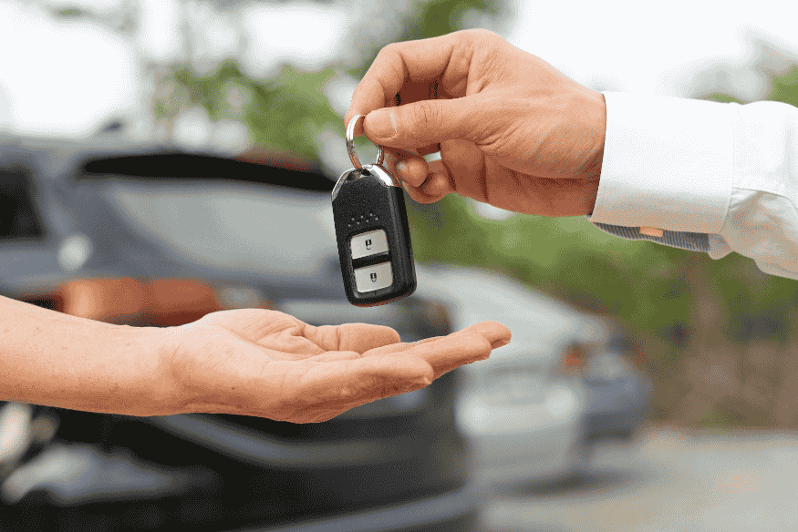 Pessoa entregando chave de carro novo após compra realizada por consórcio ou financiamento.
