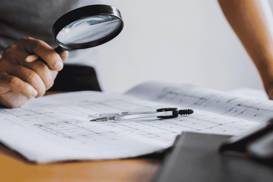 Pessoa utilizando lupa sobre documentos, simbolizando a importância de consultar regularmente o CPF para identificar dívidas ativas e proteger a saúde financeira.