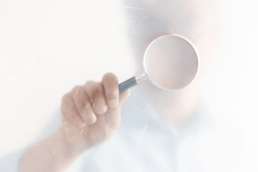 Pessoa segurando uma lupa, simbolizando a análise detalhada sobre a relação entre consultas ao CPF e o impacto no score de crédito.