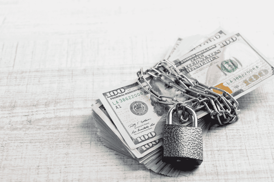 Notas de dólar presas por corrente e cadeado simbolizando segurança financeira e proteção oferecida pelo chargeback