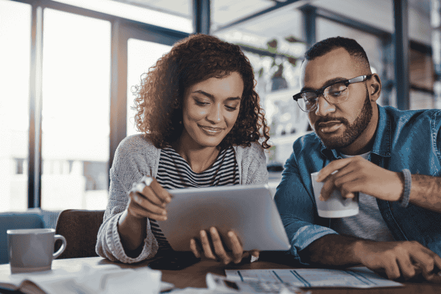Casal revisando dados financeiros em um tablet, simbolizando a importância de revisar e corrigir o relatório de crédito para manter a saúde financeira.