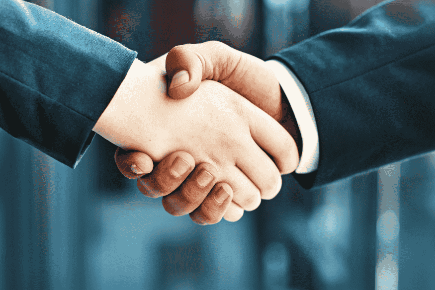 Aperto de mãos entre duas pessoas de terno, simbolizando a confiança e o acordo mútuo em operações de P2P Lending no mercado financeiro brasileiro.