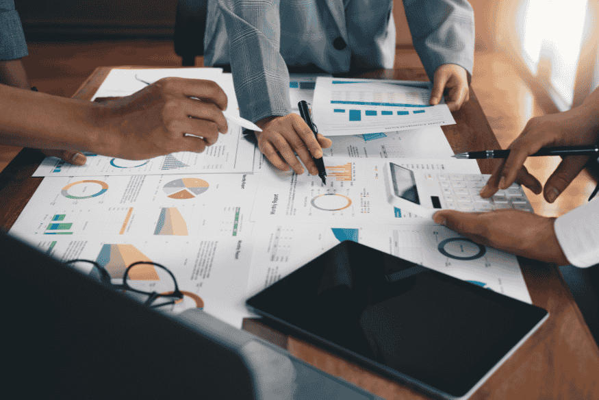 Equipe analisando relatórios financeiros com gráficos e planilhas, representando a avaliação da situação financeira antes de negociar dívidas online.