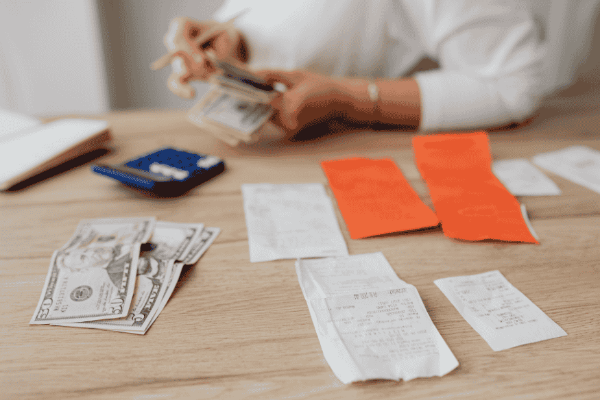 Pessoa organizando contas e dinheiro em espécie, simbolizando o parcelamento da fatura do cartão de crédito como alternativa ao rotativo