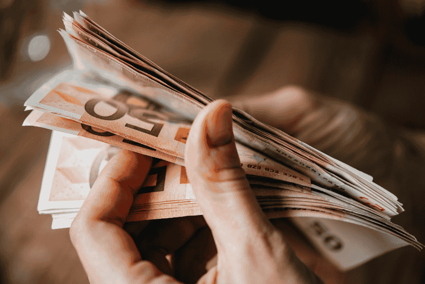 Pessoa contando notas de euro, representando a importância de tomar decisões conscientes entre parcelas fixas e variáveis para garantir estabilidade financeira.