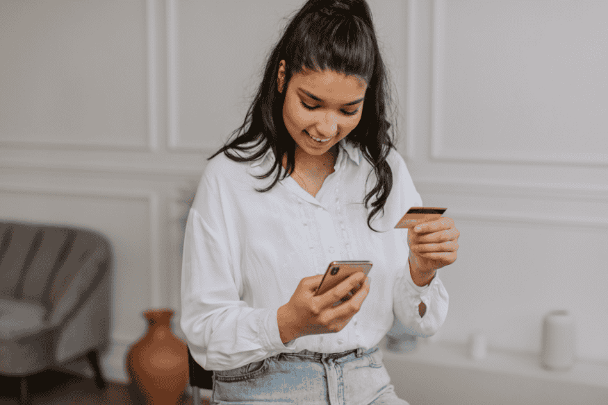 Mulher usando celular e cartão de crédito para realizar Pix no cartão, ilustrando nova flexibilidade financeira