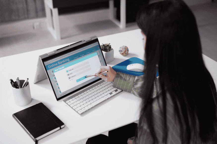 Mulher acessando internet banking em notebook para gerenciar financiamento de veículo e organizar parcelas, simbolizando renegociação online para equilíbrio financeiro.