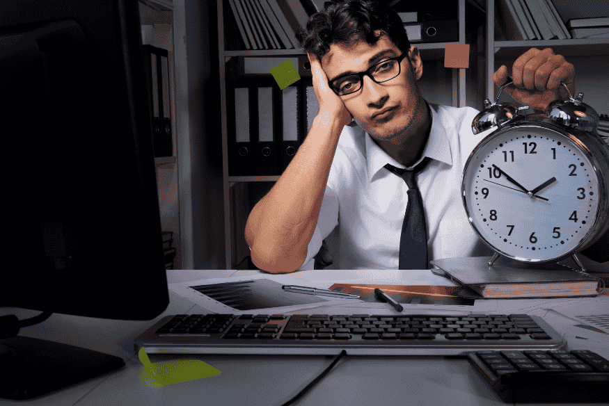 Pessoa frustrada olhando para o relógio e seu computador, simbolizando os desafios de melhorar o score de crédito e os erros financeiros comuns.