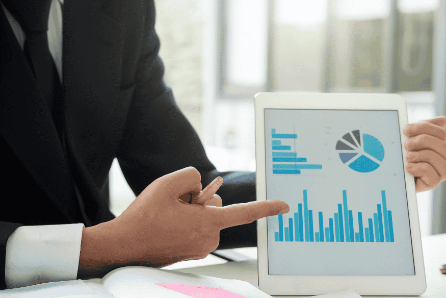Homem de negócios analisando gráficos em tablet com indicadores de score de crédito, representando as diferenças entre Serasa, SPC e Boa Vista.