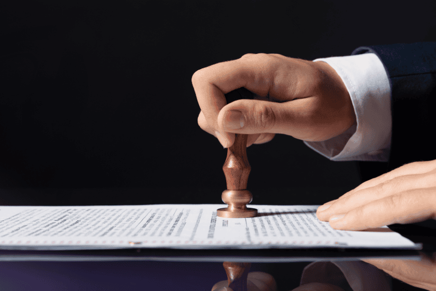 Mão carimbando documento oficial, simbolizando a quitação da dívida e o prazo legal para retirada do nome dos cadastros de inadimplentes.