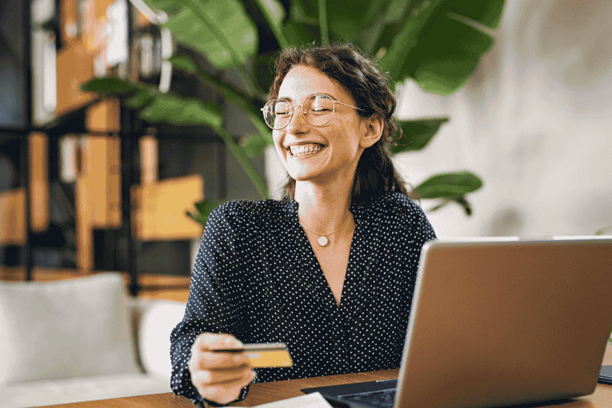Mulher feliz segurando um cartão de crédito, simbolizando a boa gestão financeira e o controle do limite de crédito para manter um score elevado.