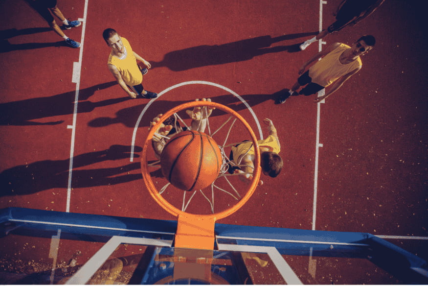 Vista aérea de uma cesta de basquete no momento da bola entrando, durante jogo 3×3 ao ar livre.