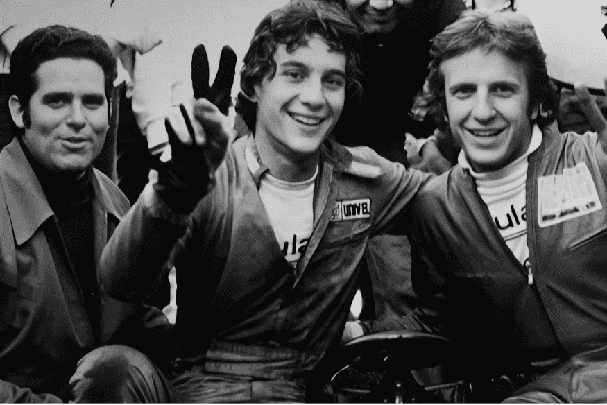 Ayrton Senna jovem sorrindo ao lado de colegas em ambiente de competição de kart.