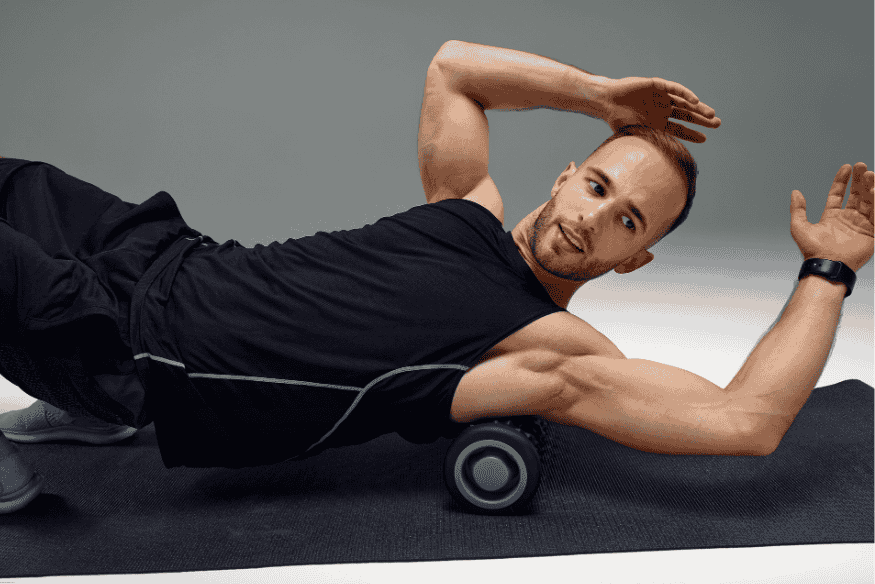 Homem utilizando foam roller para liberar a fáscia lateral do tronco durante a recuperação muscular.
