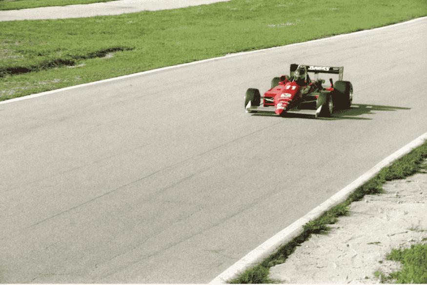 Carro antigo de Fórmula 1 em pista sem o dispositivo Halo, evidenciando evolução da segurança.