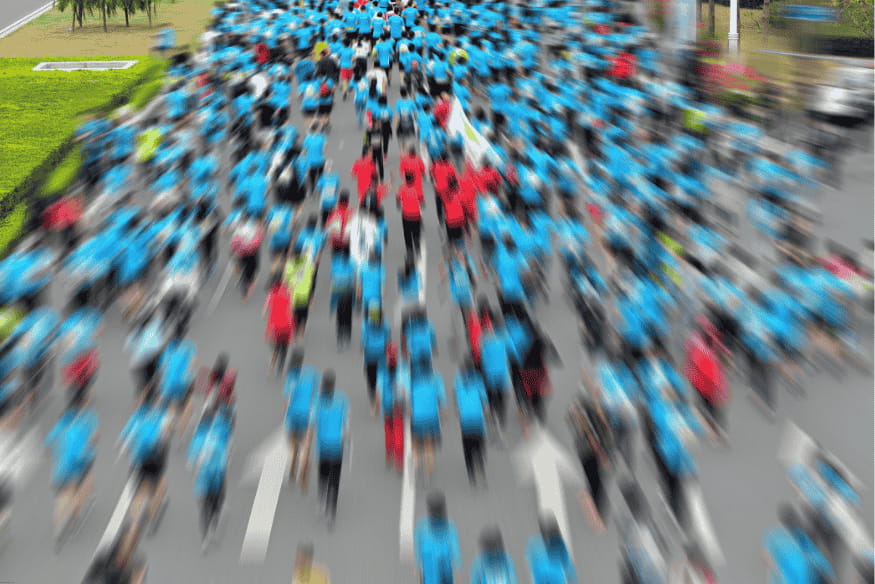 Multidão de corredores com camisetas azuis participando de uma maratona.
