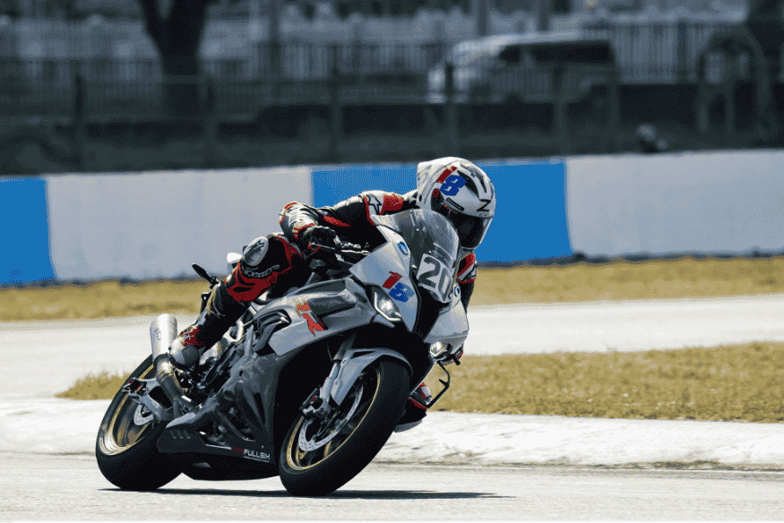 Piloto de moto esportiva fazendo curva acentuada em pista de corrida durante competição de motociclismo.