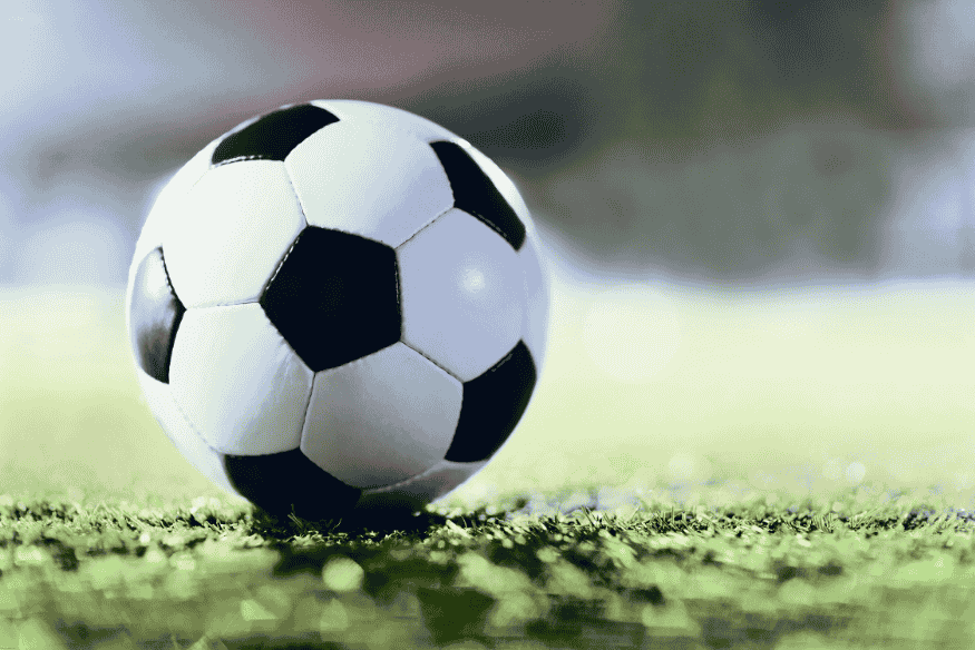 Bola de futebol em campo iluminado, representando partidas internacionais.