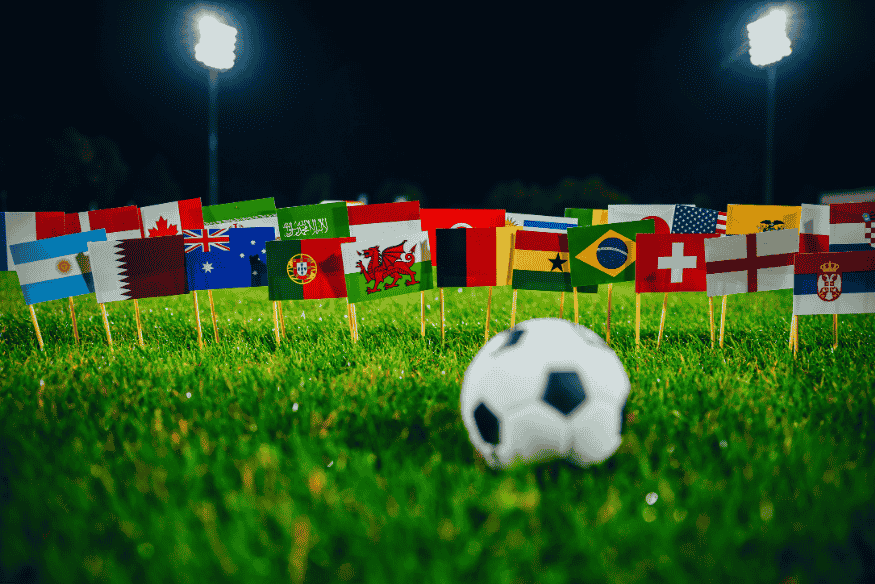 Bola de futebol cercada por bandeiras de países participantes de torneios internacionais.