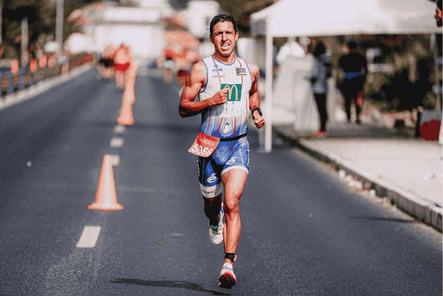 Corredor masculino em pista de atletismo com passada longa e cadência controlada.