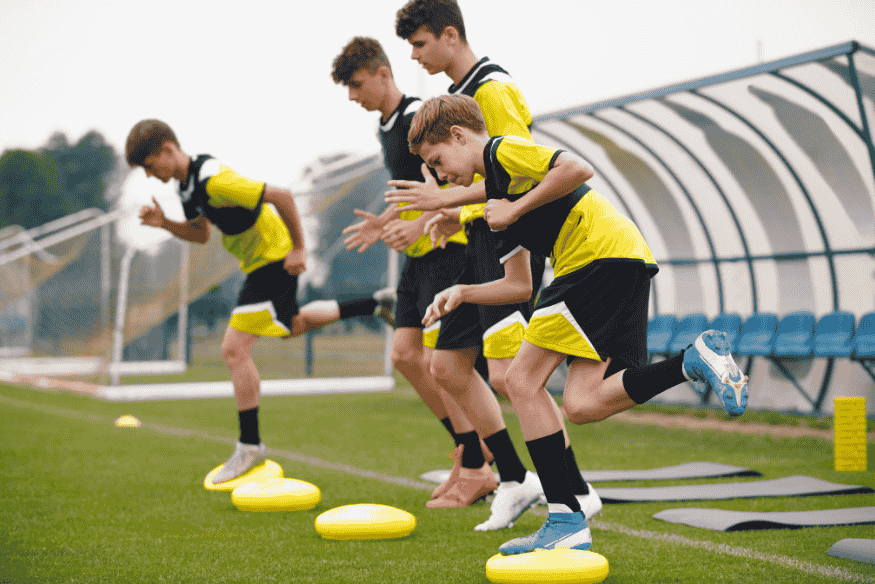 Grupo de jovens jogadores fazendo exercícios físicos em treino tático.