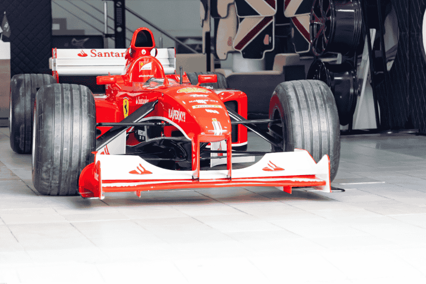 Carro de Fórmula 1 da Ferrari em exibição, com design aerodinâmico e pneus largos.