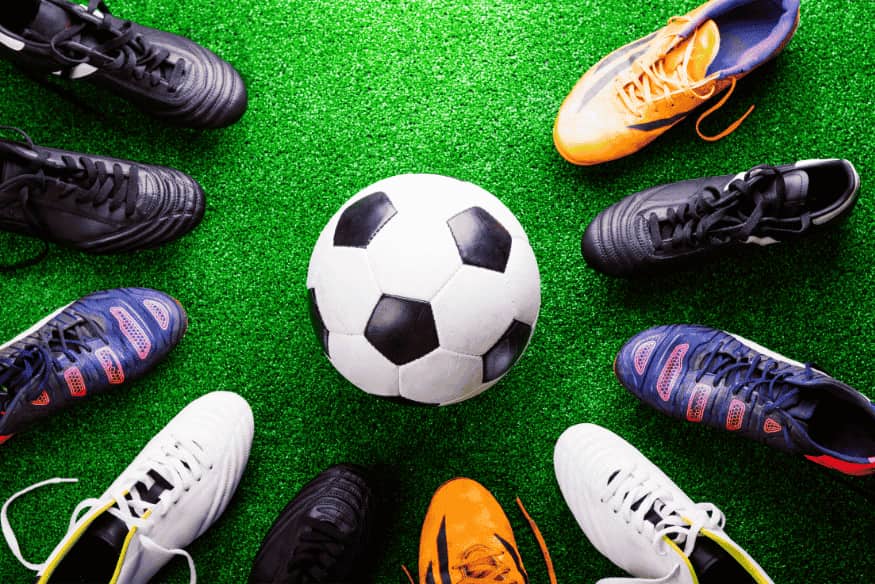 Diversas chuteiras coloridas formando um círculo ao redor de uma bola
