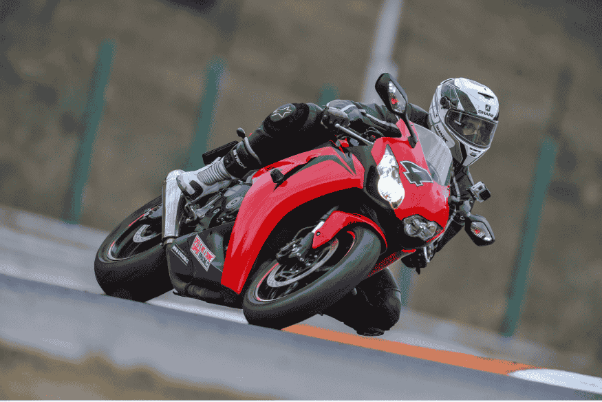 Piloto de moto esportiva inclinando em curva de pista durante corrida.