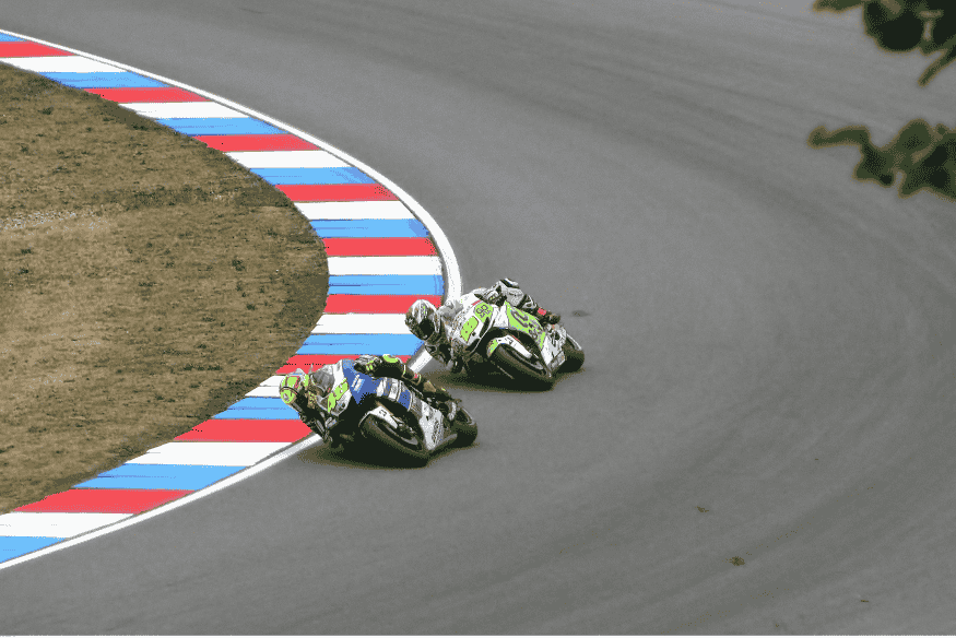 Dois pilotos disputando posição lado a lado em curva, inclinando motos de forma extrema.