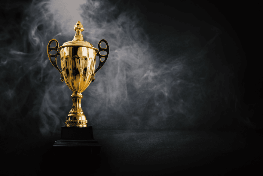 Troféu dourado de futebol envolto por fumaça em fundo escuro