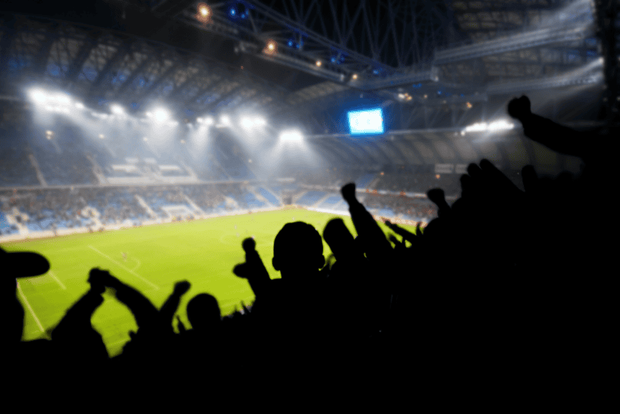 Torcedores comemorando em estádio lotado durante partida de futebol no Brasil.