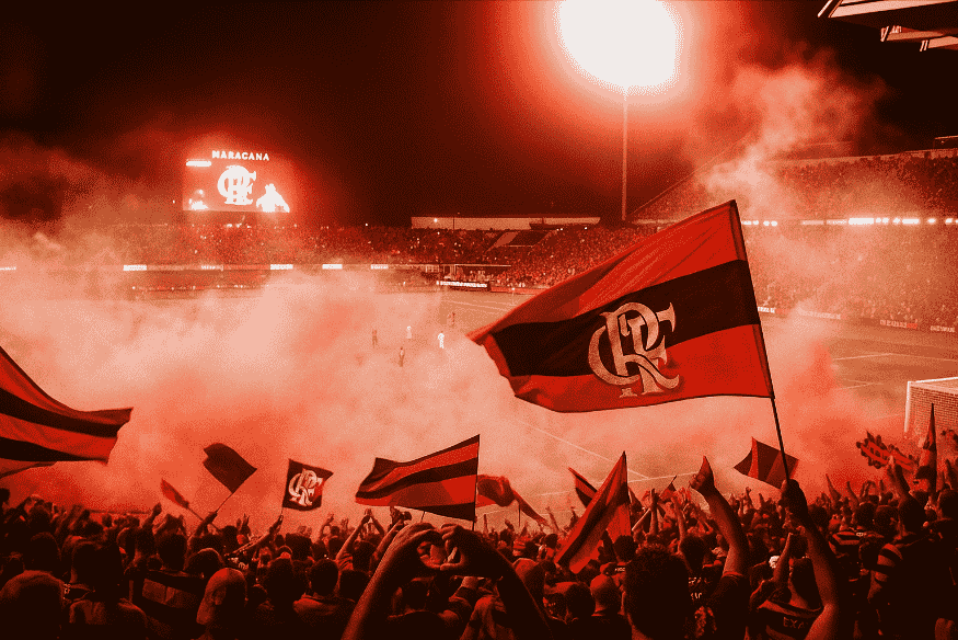 Torcida do Flamengo com bandeiras e sinalizadores no Maracanã à noite.
