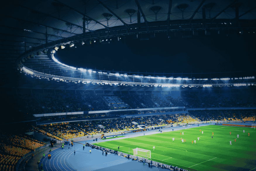 Estádio iluminado com torcida acompanhando partida decisiva
