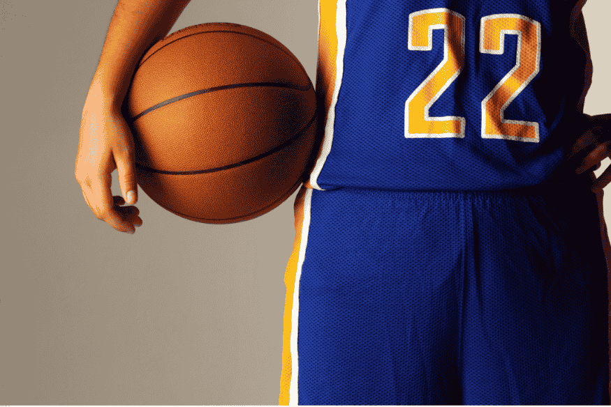 Close de jogador segurando bola de basquete com uniforme universitário número 22.