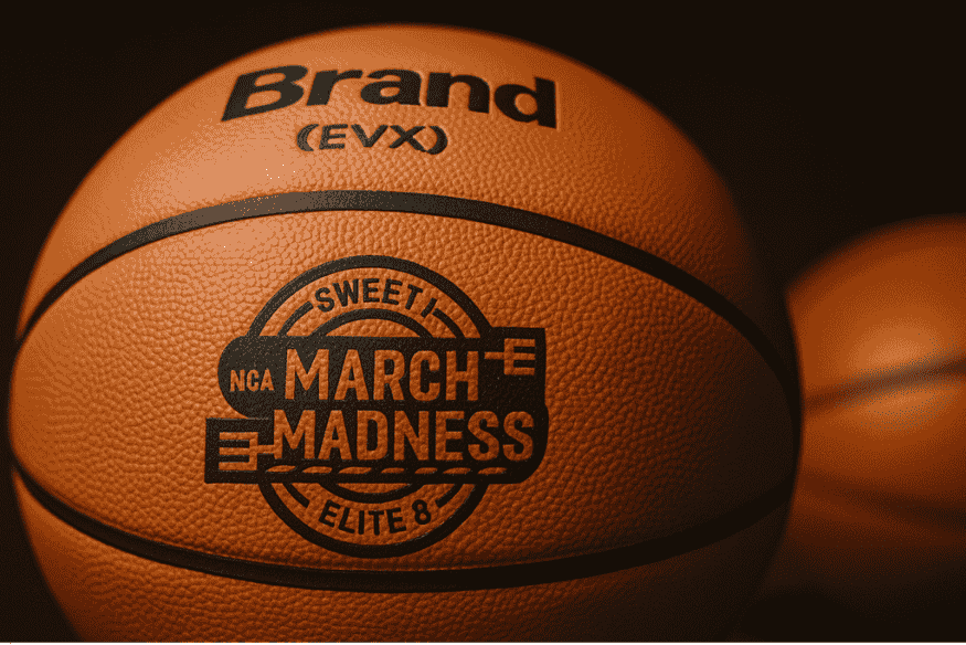 Bola oficial do torneio March Madness da NCAA com logotipo destacado, apoiada em suporte.