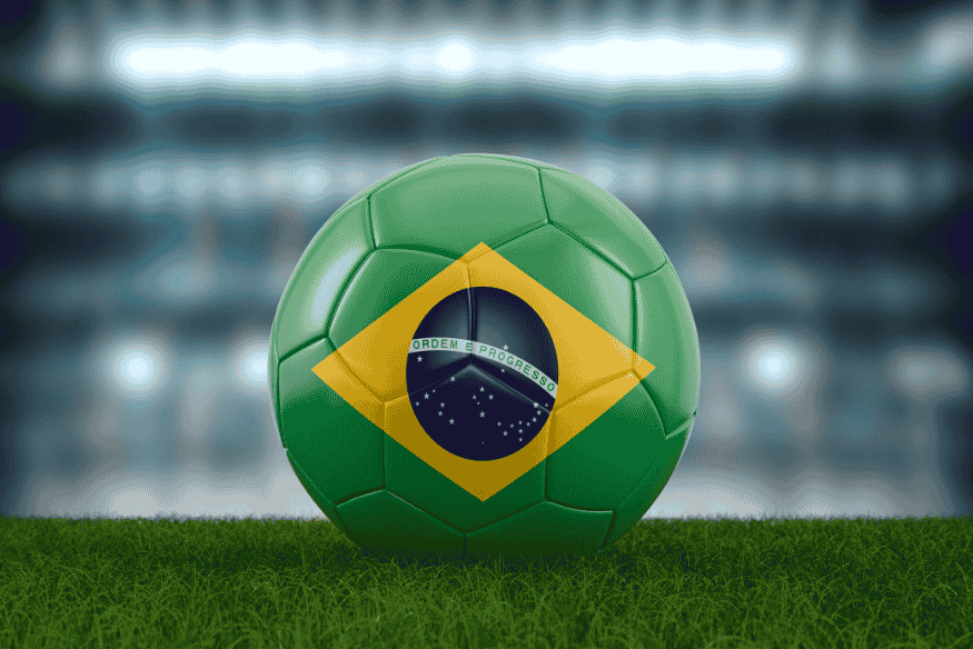 Bola de futebol verde com a bandeira do Brasil no gramado de um estádio
