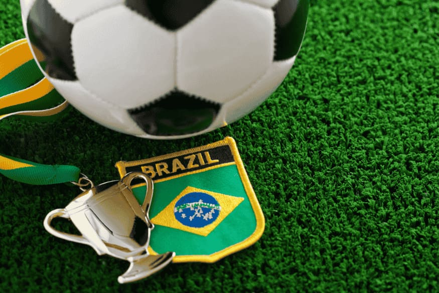 Bola de futebol, medalha e escudo do Brasil sobre grama artificial