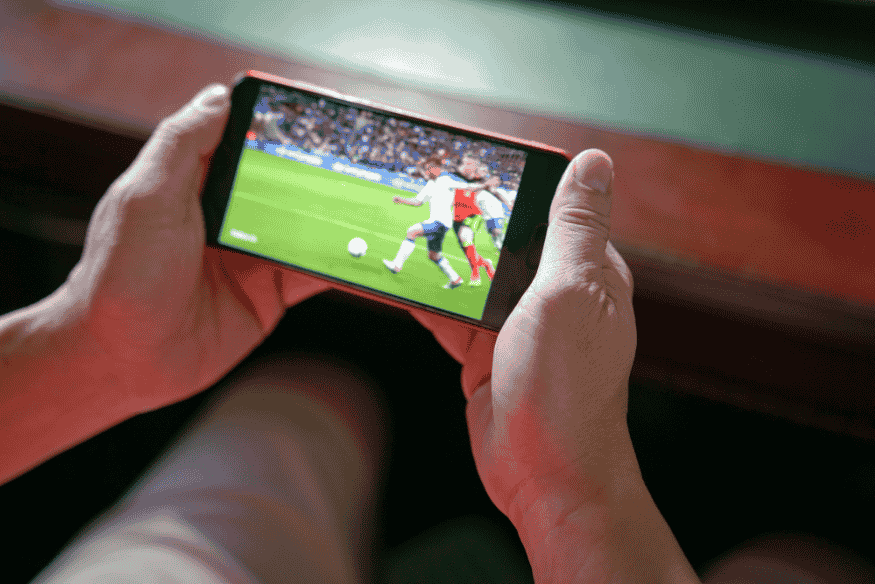 Pessoa assistindo a um jogo de futebol ao vivo em um smartphone.