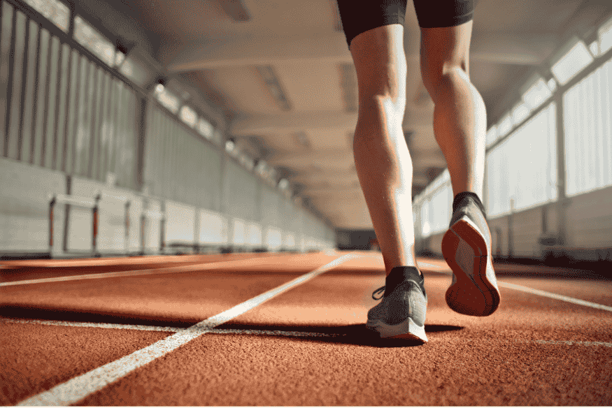 Pessoa caminhando ou correndo em pista coberta de atletismo.