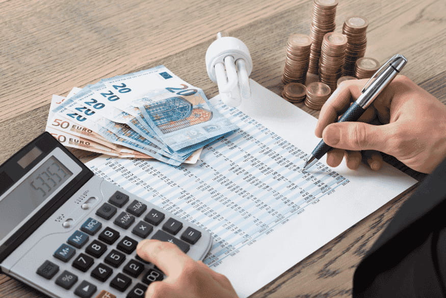 Pessoa calculando custos financeiros com calculadora, planilha, moedas e cédulas de euro, simbolizando a importância do Custo Efetivo Total (CET) na contratação de crédito consciente.