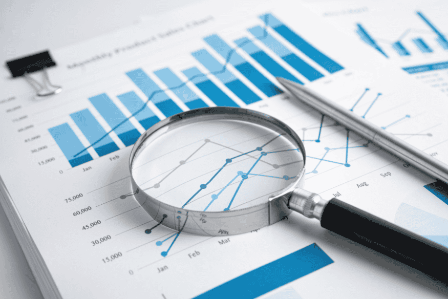 Lupa sobre gráficos financeiros em relatórios, simbolizando o acompanhamento após a quitação da dívida e a importância de monitorar o score de crédito.