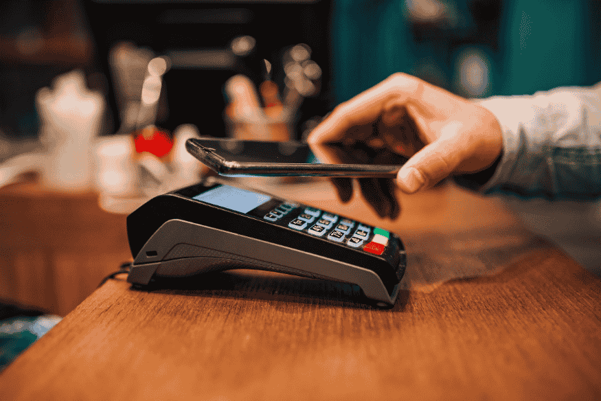 Pagamento por aproximação com celular em maquininha de cartão, ilustrando o uso de Pix por aproximação no dia a dia.